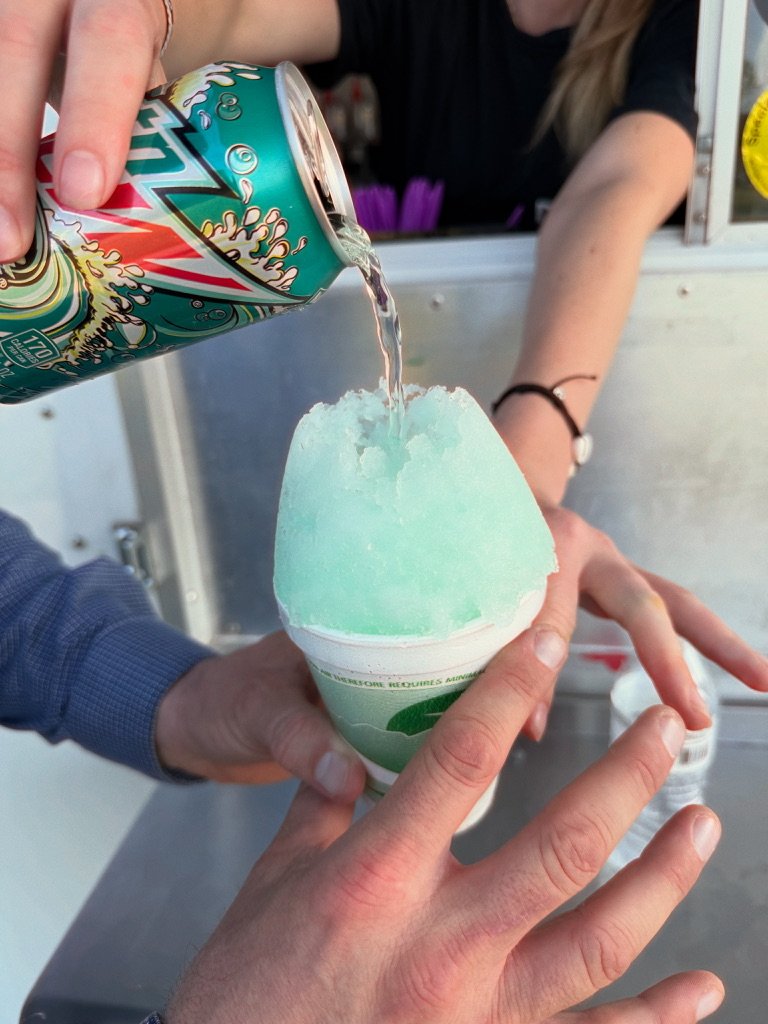 A drink being poured over a shaved ice cup at the trailer window